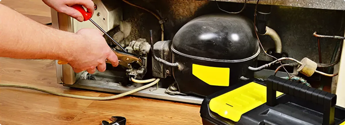 Refrigerator repair technician fixing the compressor and wiring in Loxahatchee, FL