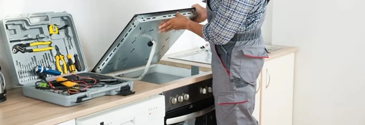 Cooktop repair technician lifting a built-in stovetop for service in West Palm Beach, FL
