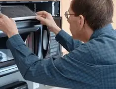 Appliance repair technician replacing a microwave vent filter in West Palm Beach, FL