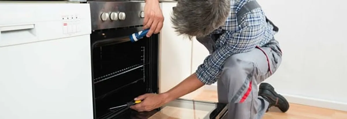 Oven repair technician inspecting and servicing an electric oven in West Palm Beach, FL